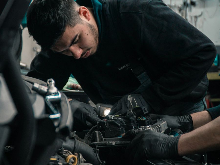 Technician working under the hood of a vehicle in the service bay