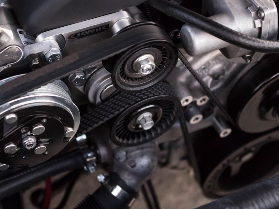 Close-up of engine belts and pulleys during a mechanical repair