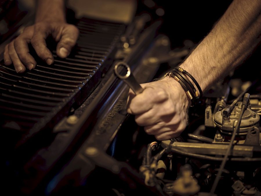 Hands tightening an engine bolt with a wrench