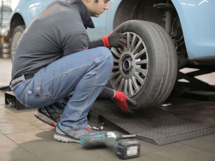 Technician mounting a wheel on a lifted car